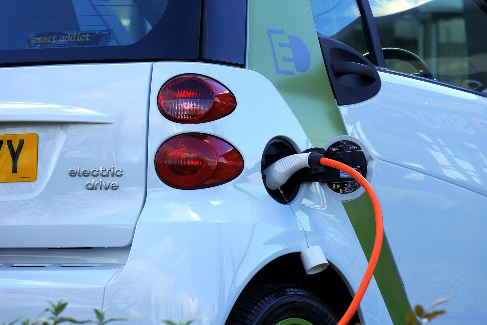 Vehículo eléctrico conectado a carga en un entorno urbano e industrial.