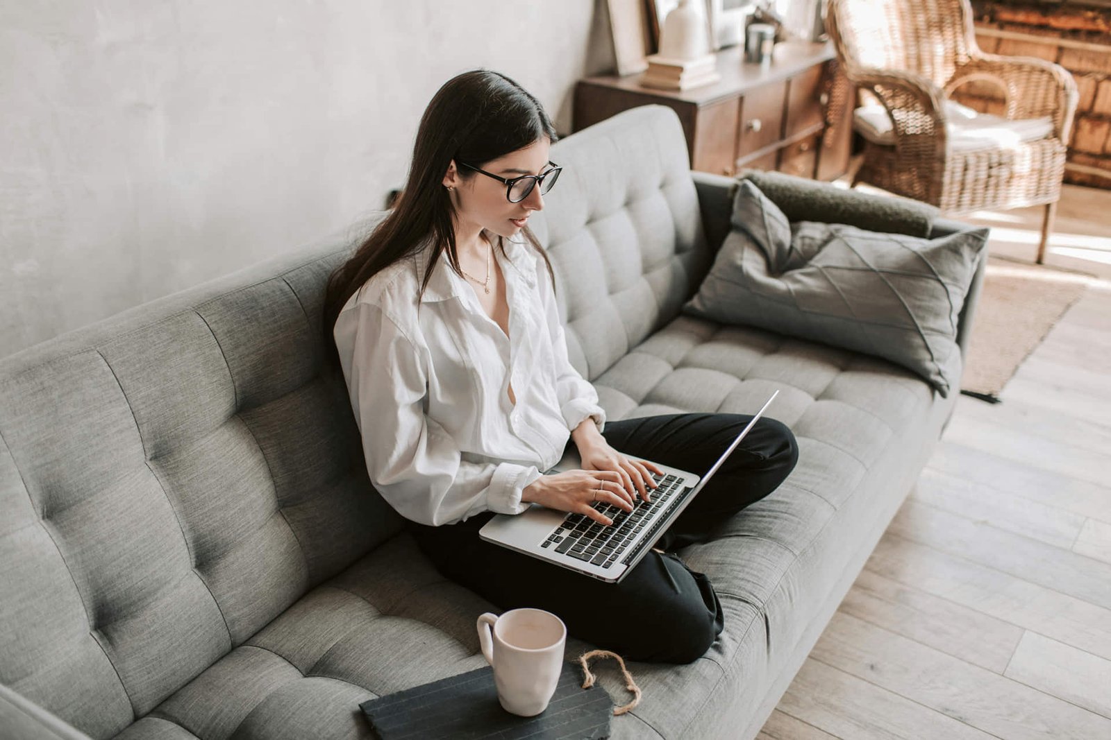 Persona trabaja desde casa con laptop y silla ergonómica en un espacio ordenado.