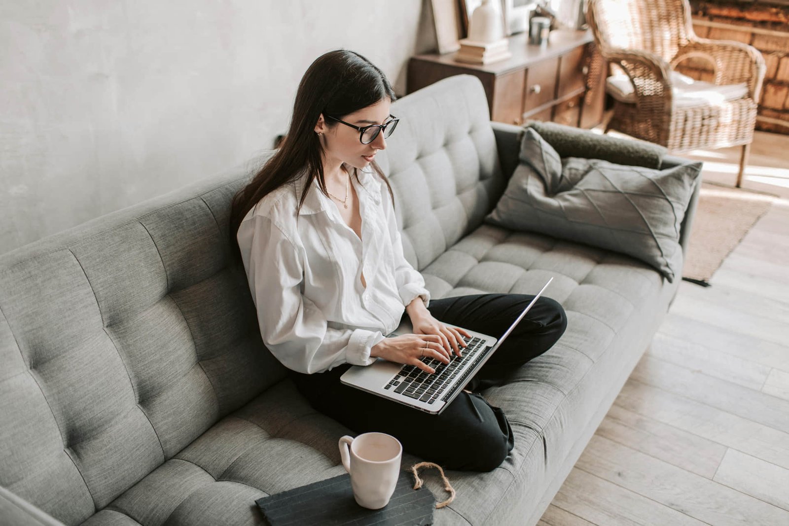 Persona trabaja desde casa con laptop y silla ergonómica en un espacio ordenado.