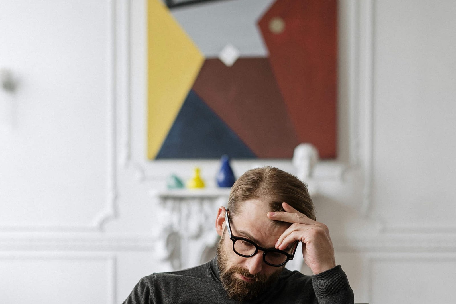 Mujer profesional con gafas, sonriendo con confianza y mirando hacia arriba en un entorno de oficina moderno y luminoso.